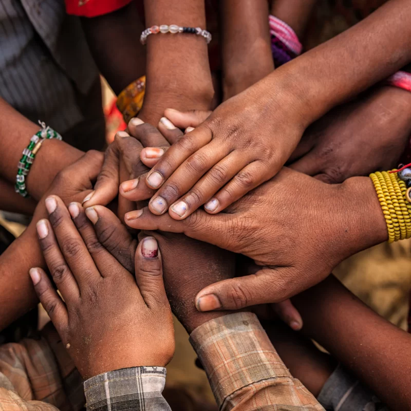 A diverse group people holding out their hands placing them on top of each other in a circle - teamwork- togetherness