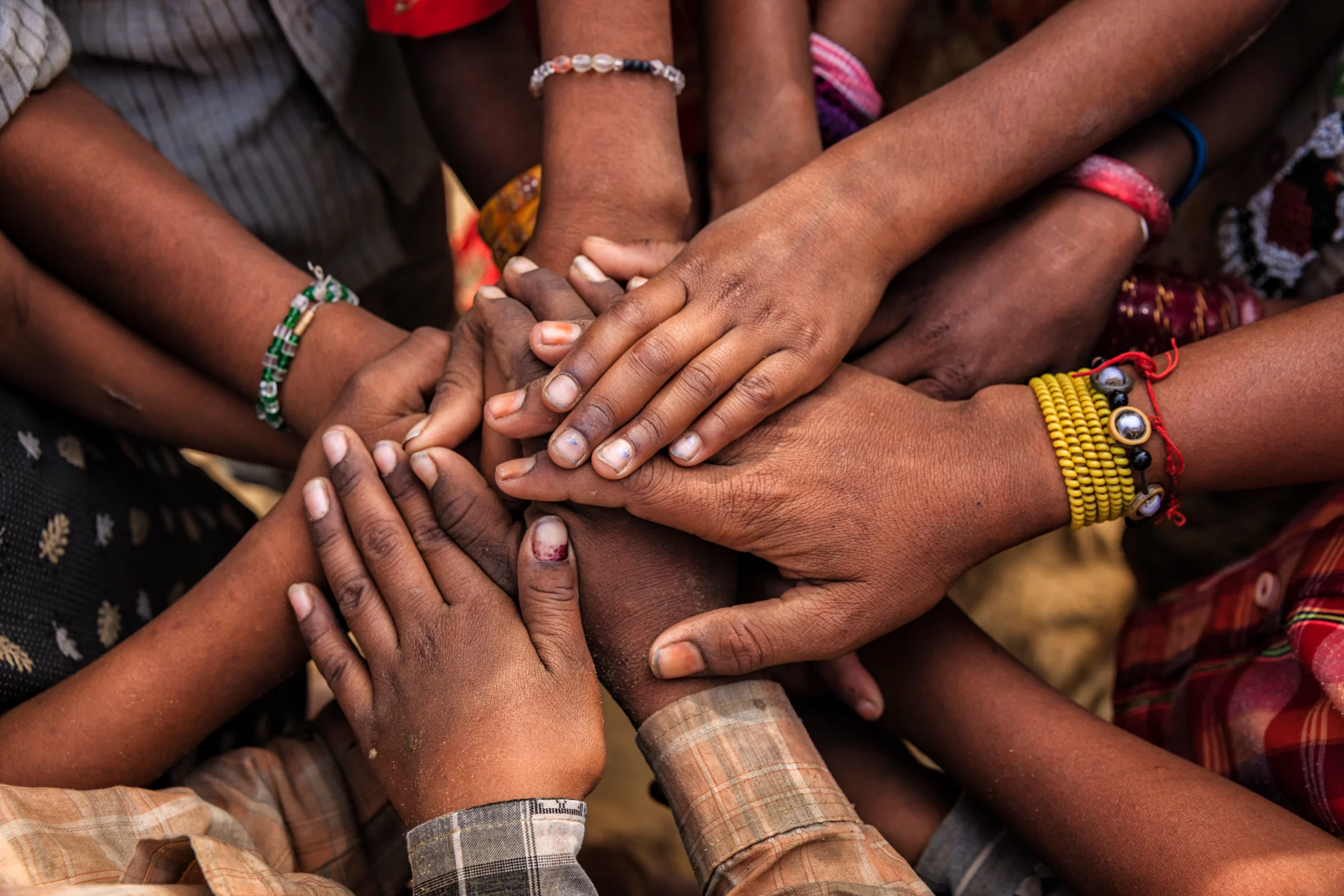 A diverse group people holding out their hands placing them on top of each other in a circle - teamwork- togetherness