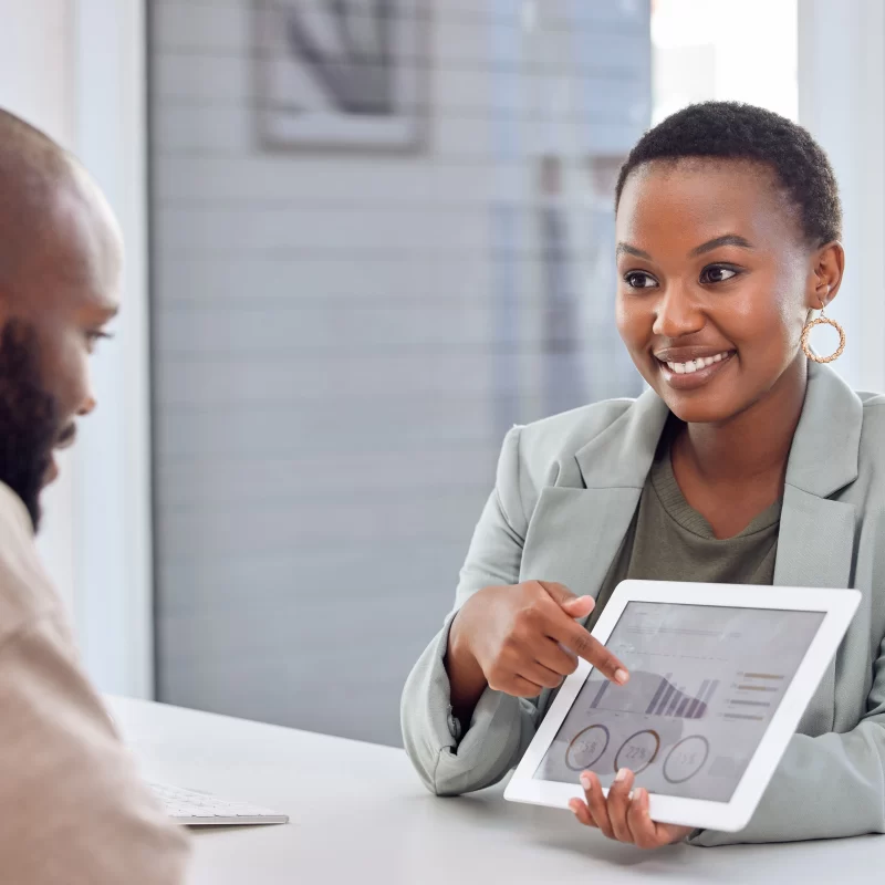 Short hair smiling lady showing analytics metrics to a gentleman on a table across her